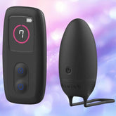 The B Swish Bnaughty Unleashed Deluxe Wireless Remote-Controlled Bullet Vibrator, in black, is pictured with its matching remote against a pastel purple and pink background, highlighting its waterproof design and discreet power buttons.